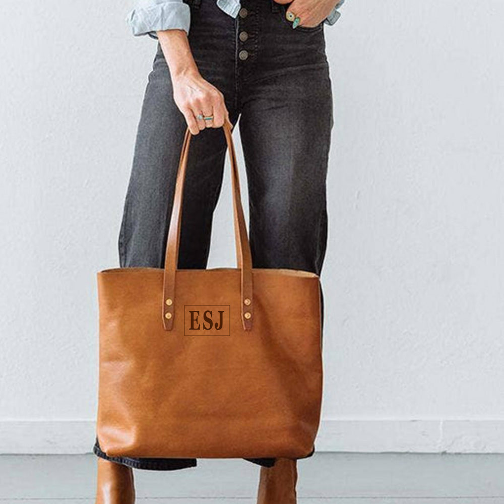Close-up of laser engraved initials on tan leather tote